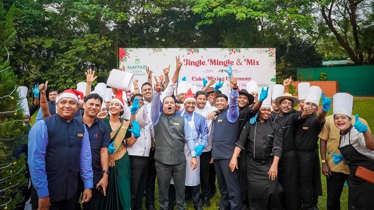 Cheerful hotel staff posing outdoors during a Christmas-themed event with festive hats and gloves.